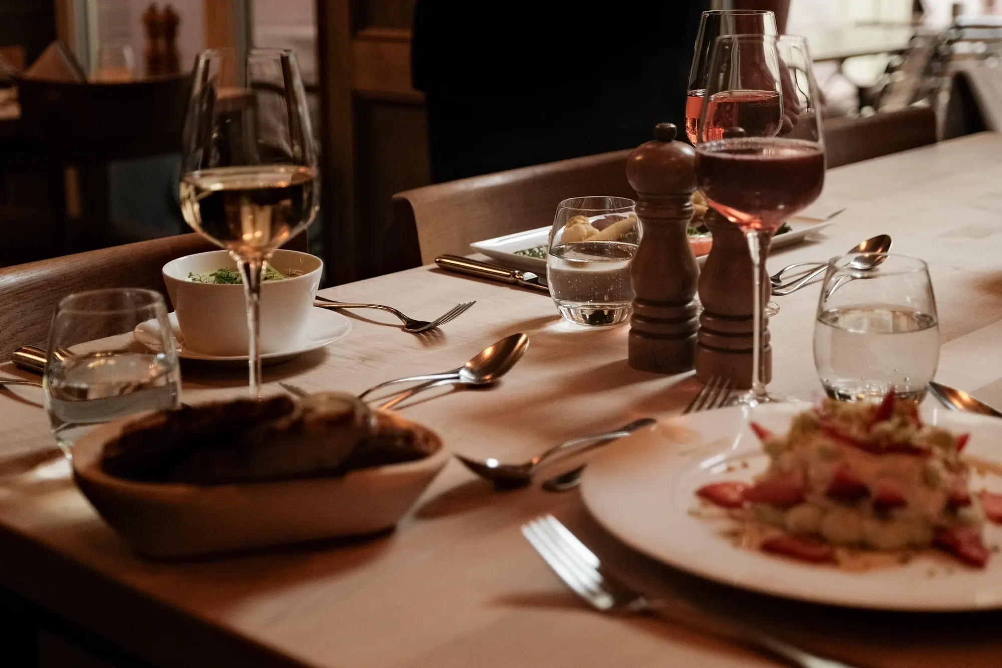 Gedeckter Tisch mit Wein, Brezel und Gerichten aus der Wirtshausküche